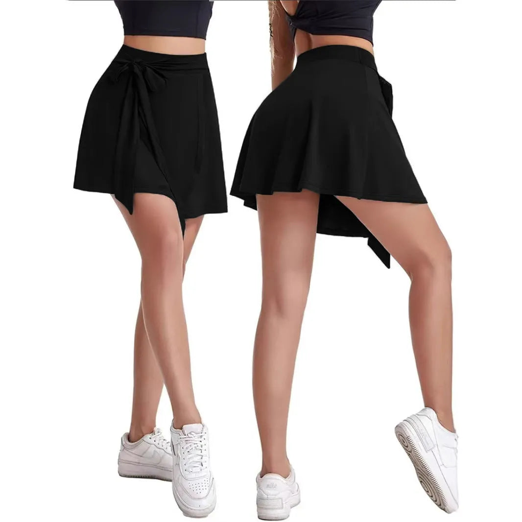 Black thigh-length sports skirt with high waist and built-in shorts, showing shoulder strap detail.