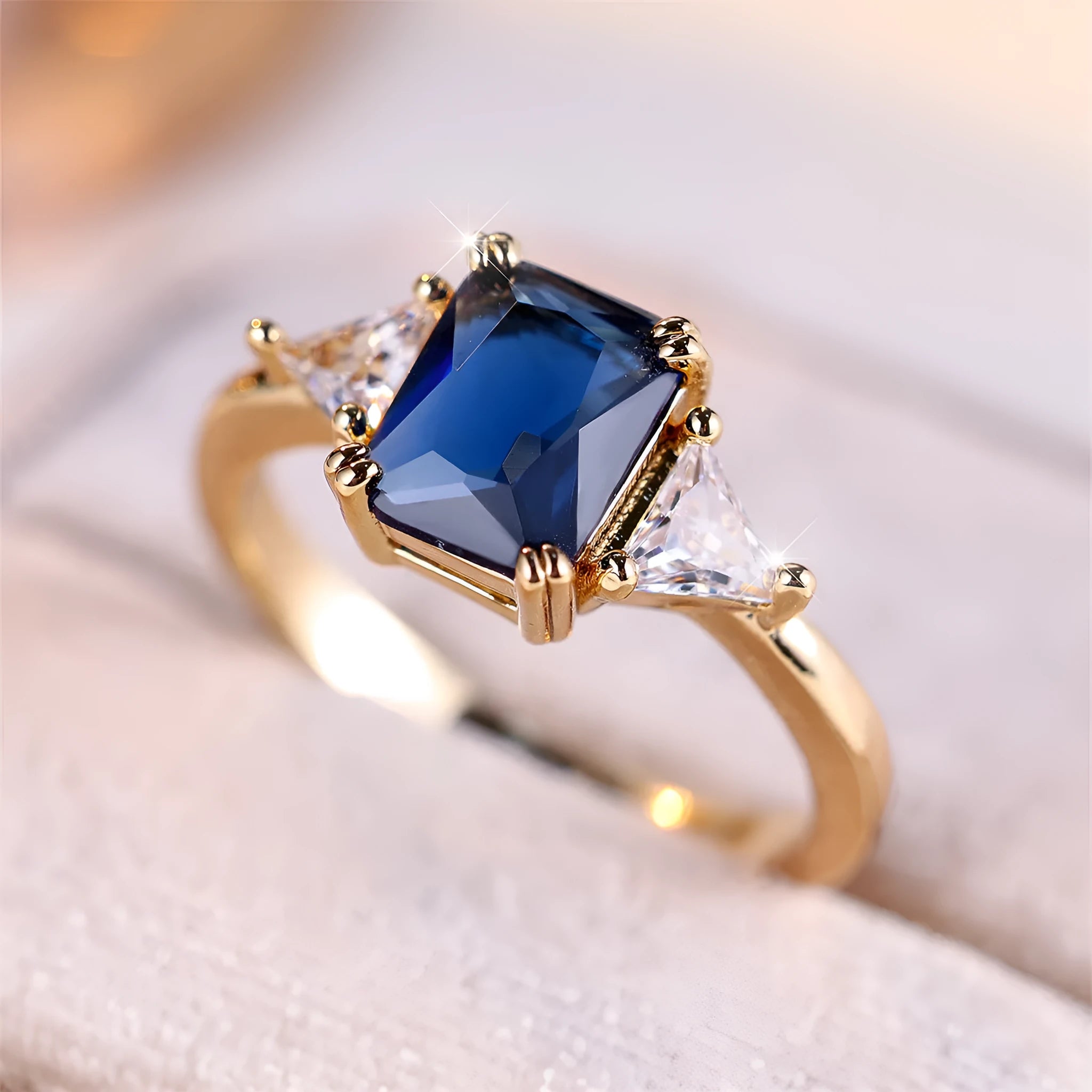 A rectangular copper fashion ring for women with a gold sapphire blue finish.