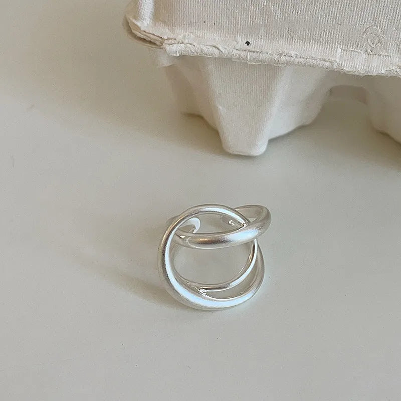 Geometric open ring with three-dimensional interlaced matte metal construction in gold or silver finish