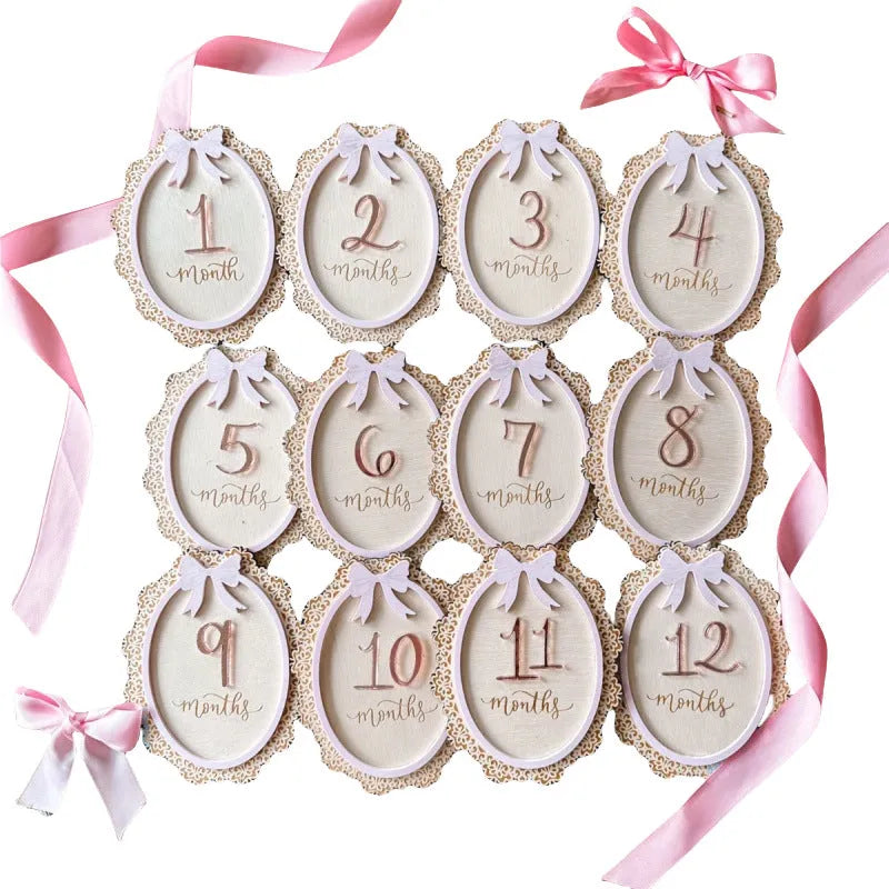 Carved boxwood lace frame bow baby milestone card with ten number stickers on a white background