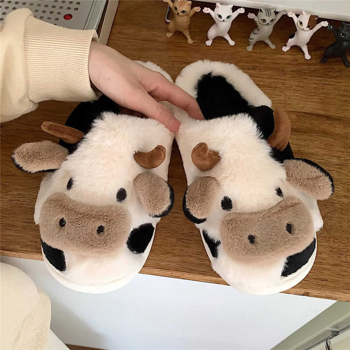 White cow print faux fur slippers for women with a non-slip textured sole.