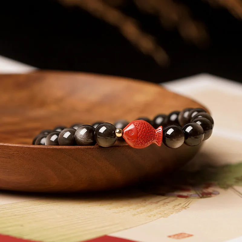 Natural obsidian round bead bracelet with red cinnabar fungus decorative elements.