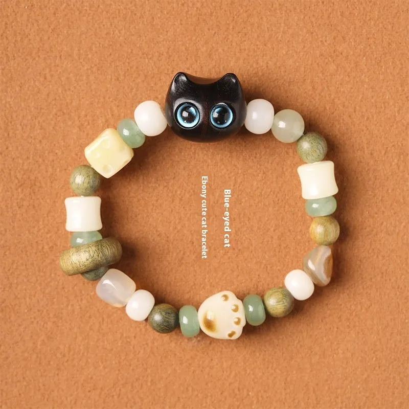 Hand-woven Buddhist bracelet with jade beads, wood elements, and cat's paw charm in rosewood or ebony with yellow or blue eyes