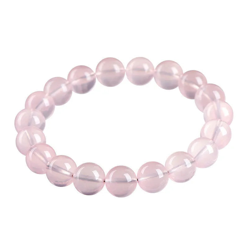 A pink natural crystal bead bracelet with polished round beads in a single circle design on a wrist.