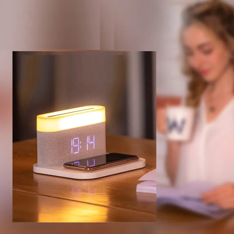 White bedside table lamp with integrated digital clock and wireless phone charging pad on base.