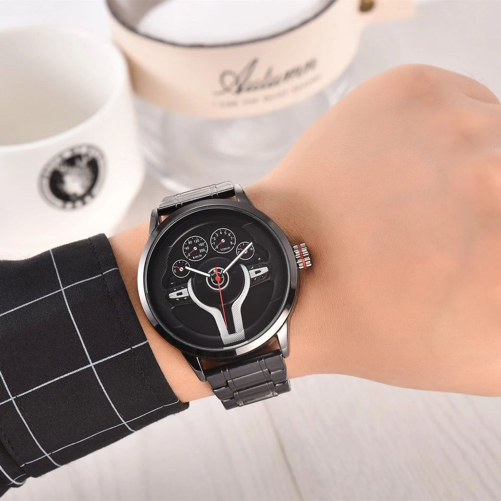 Steering wheel fashion watch with 43mm circular alloy case, stainless steel strap, and pointer display on a light background.