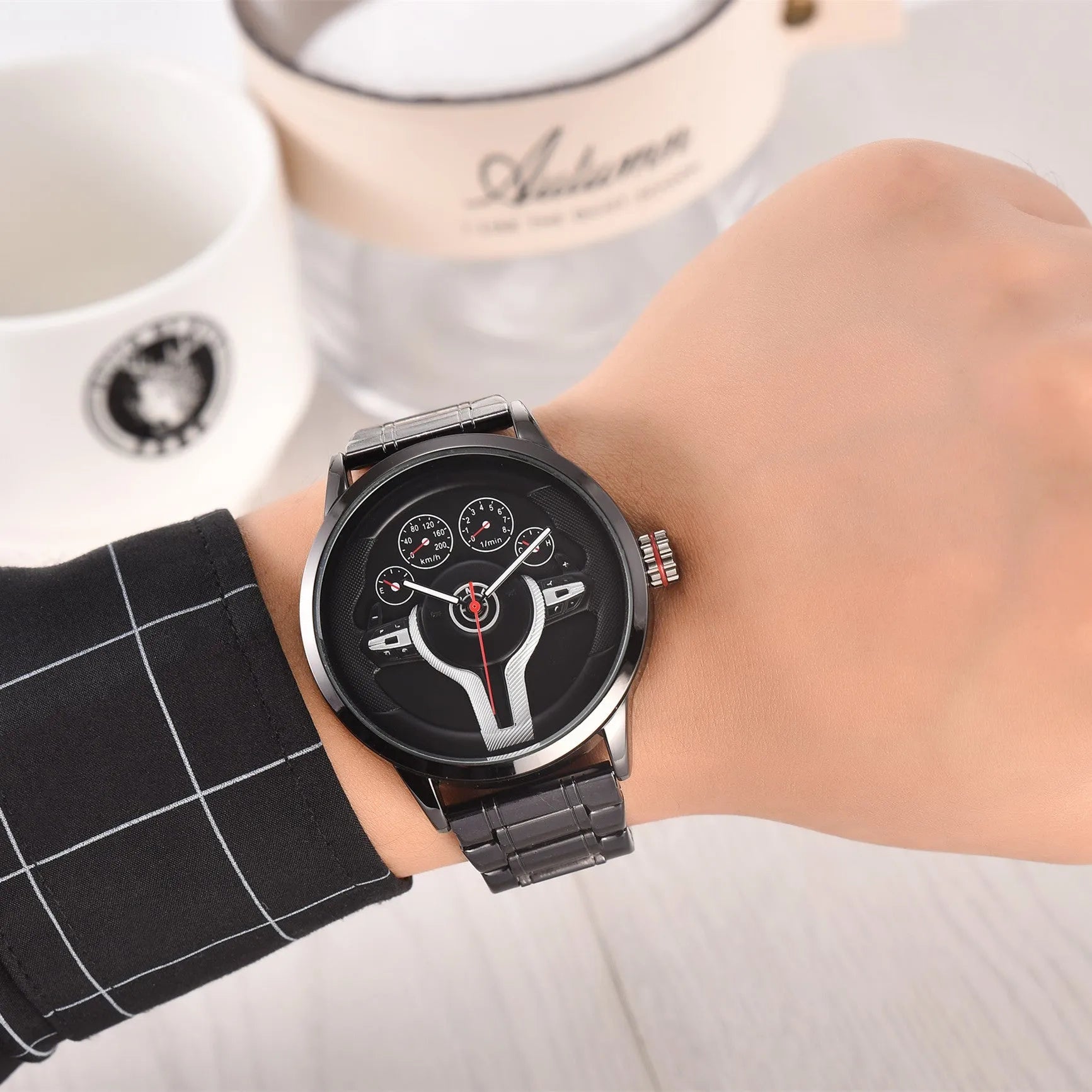 Steering wheel fashion watch with 43mm circular alloy case, stainless steel strap, and pointer display on a light background.