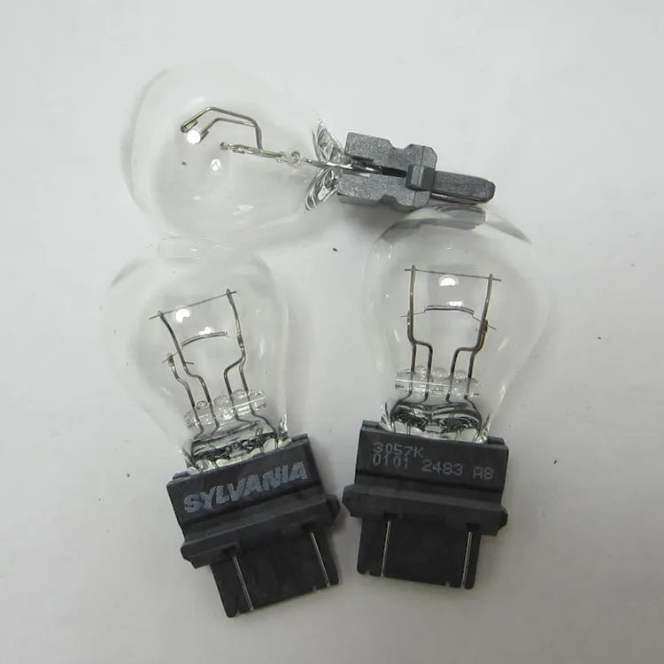 Wagner dual-wire brake light bulb with yellow glass and plastic orientation dot.