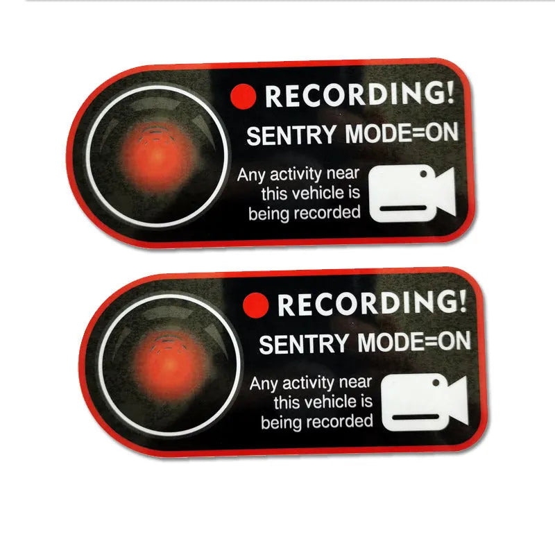 Pair of white rectangular Tesla Sentry Mode warning stickers with black text, 11cm by 5cm.