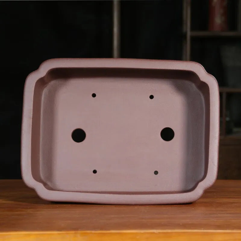 Classical rectangular purple sand bonsai pot with cut corners on a floor.