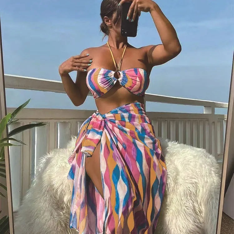 Women's three-piece bikini set with swimsuit top, briefs, and matching printed beach skirt in polyester fabric