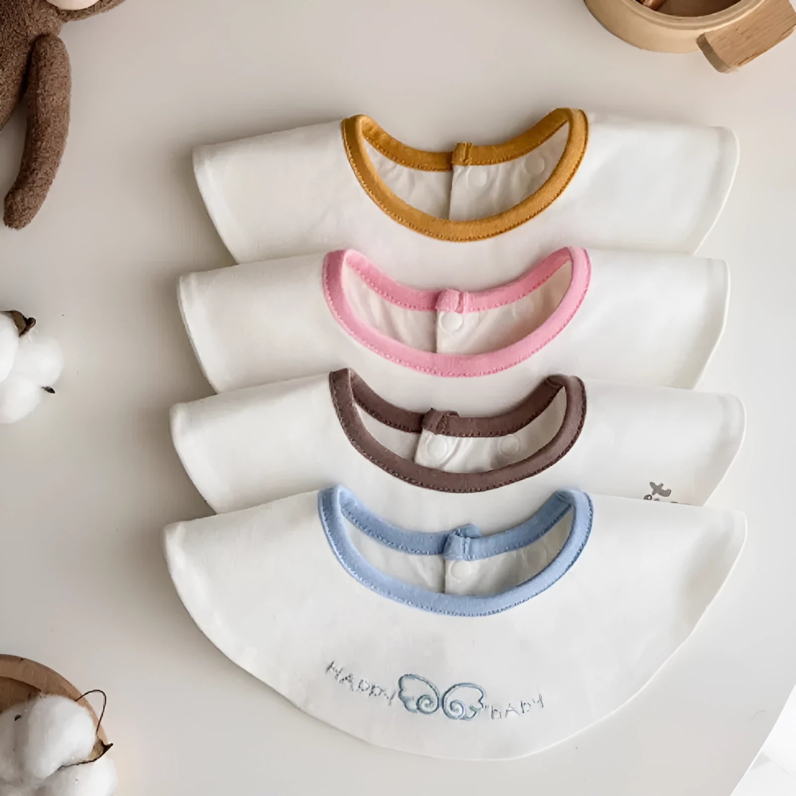 Set of three small cotton baby bibs in assorted colours with waterproof layer for milk spill protection