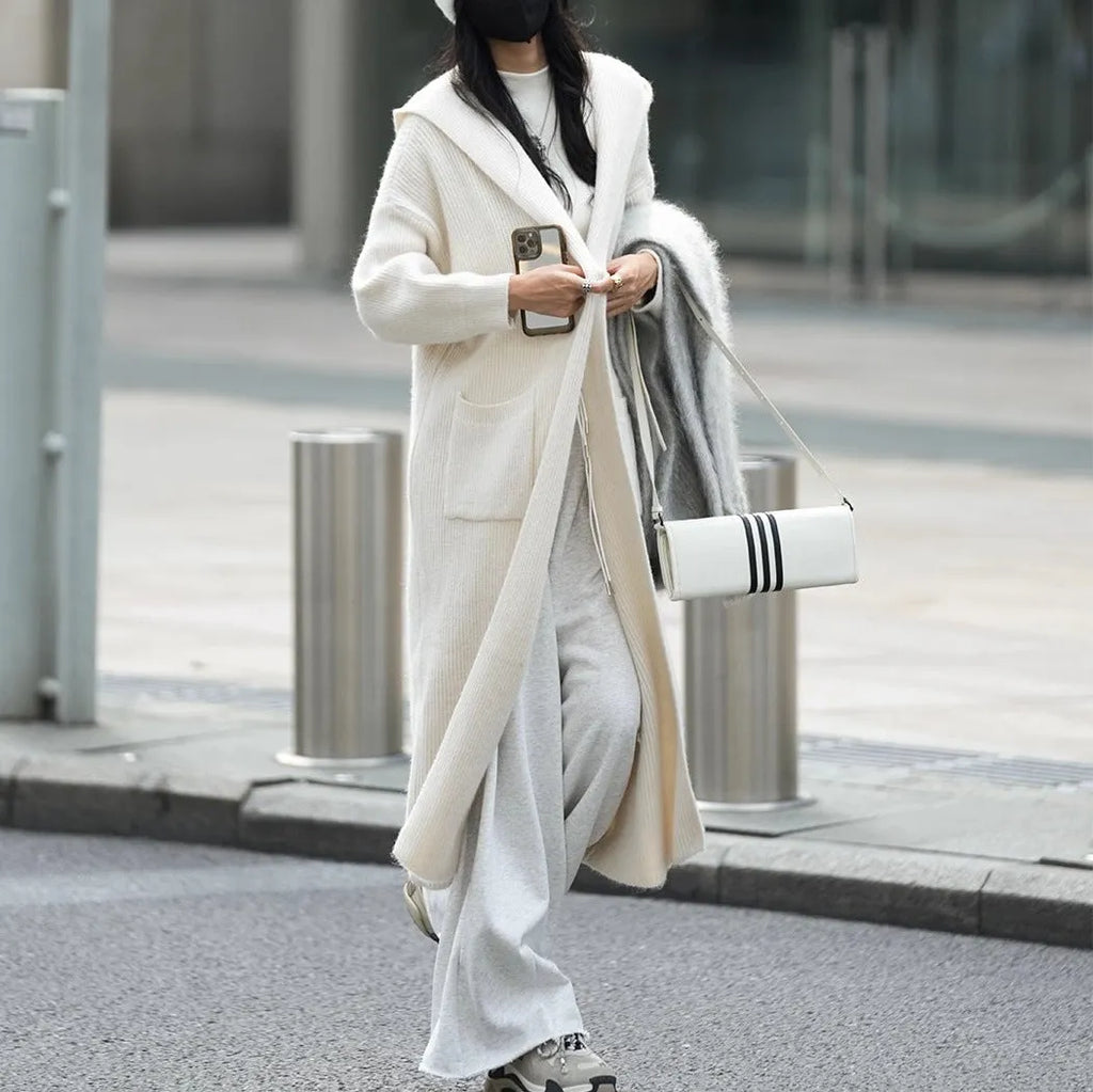 Long grey knitted hooded trench coat cardigan on a hanger, showing loose fit and long sleeves.