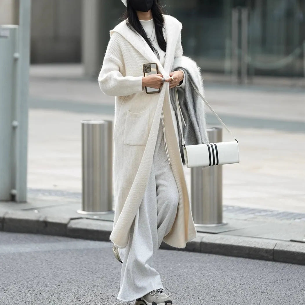 Long grey knitted hooded trench coat cardigan on a hanger, showing loose fit and long sleeves.
