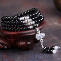 Black agate geometric bead bracelet with 108 beads and number details on a wrist.