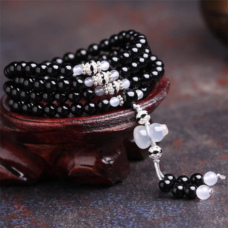 Black agate geometric bead bracelet with 108 beads and number details on a wrist.