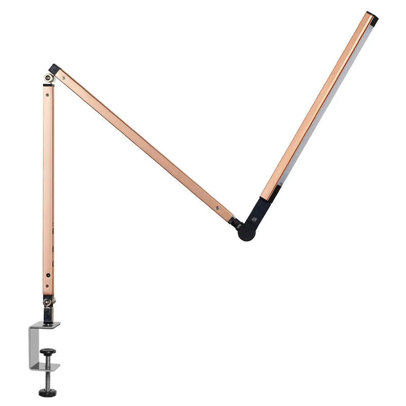Aluminium clip-on desk lamp with adjustable arm and remote control on a wooden desk.