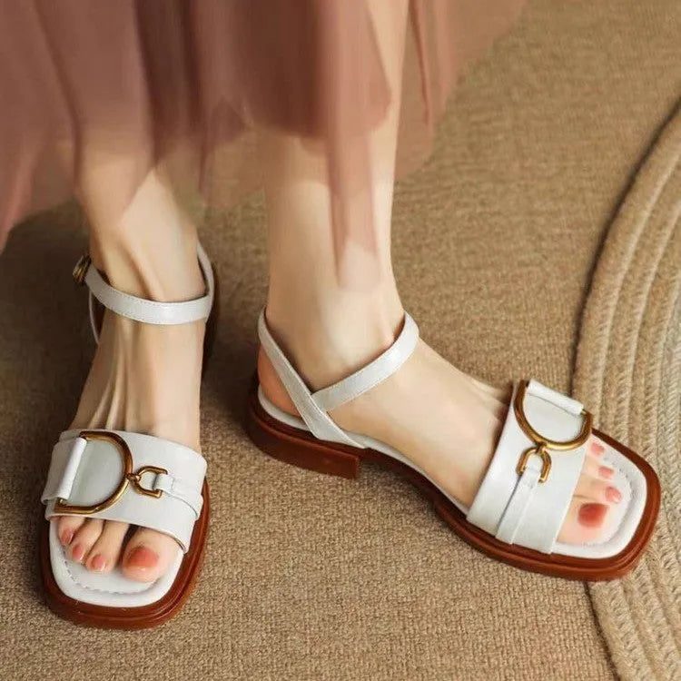 Women's beige leather sandals with a thick rubber sole and a single button closure on the strap.