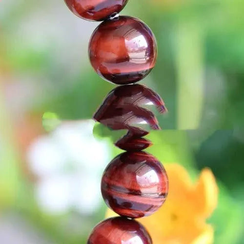 Red Tigereye wood alexandrite hand bracelet showing lightning cat's eye pattern with geometric ethnic style design