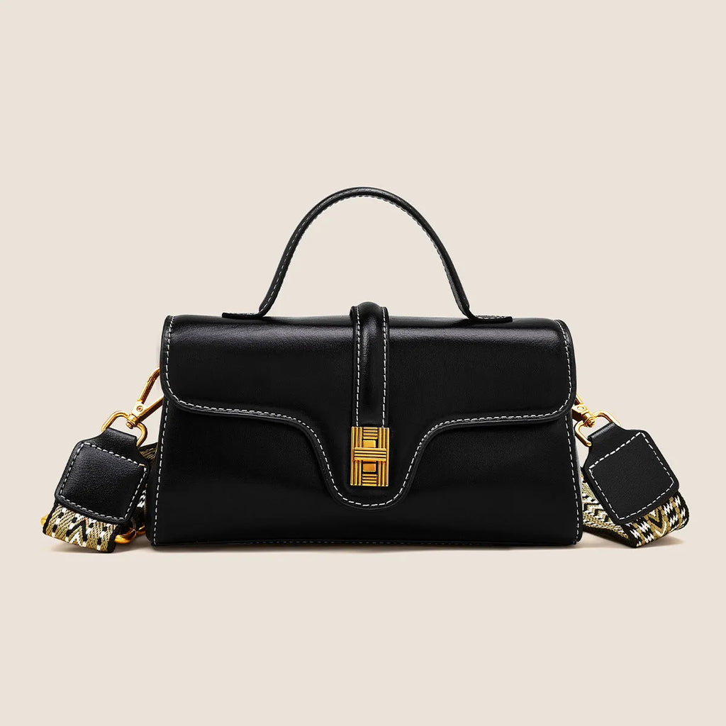 Brown Cambridge-style crossbody messenger bag with clamshell opening and lock detail on a table.