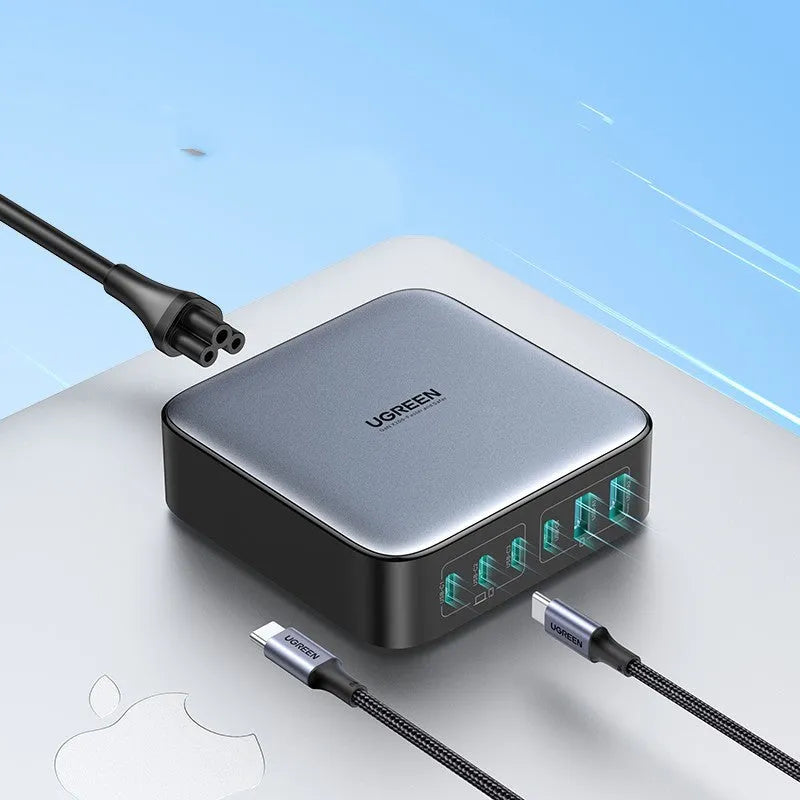 100W Gallium Nitride fast wall charger with USB-C port on a desk next to a laptop.