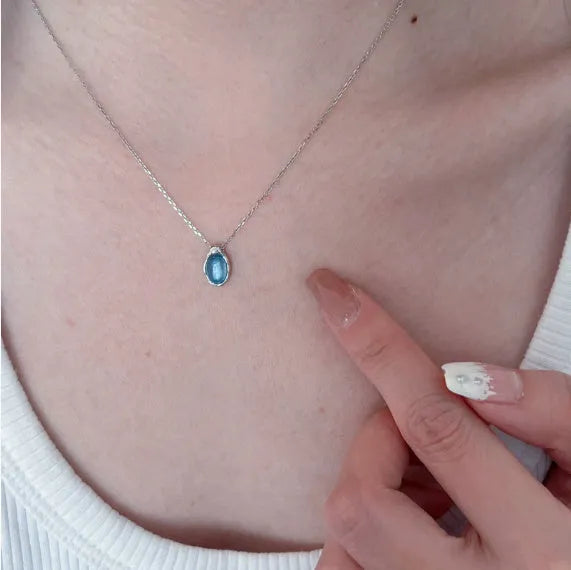 Close-up of a navy blue and platinum coloured geometric water drop pendant necklace on an adjustable copper chain.