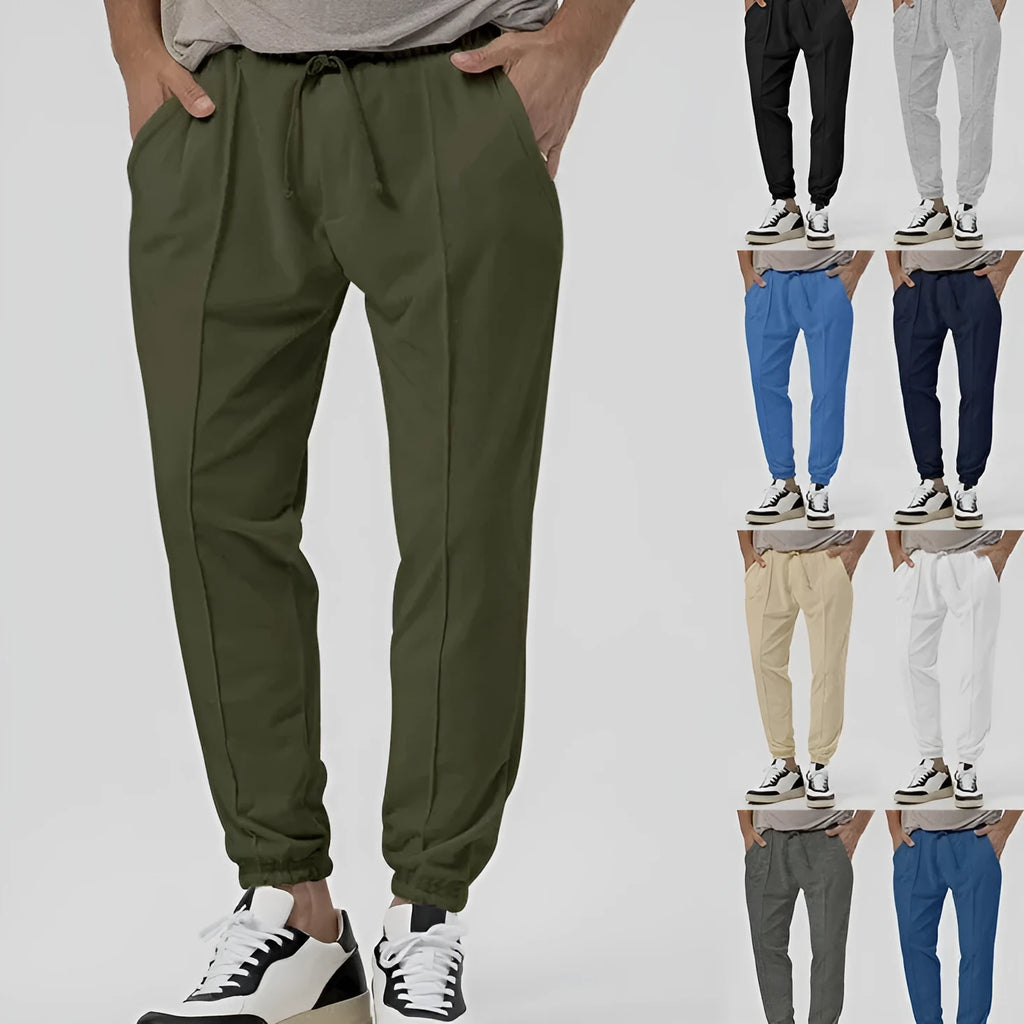 Man wearing grey loose tapered cotton blend track sweatpants, showing straight-leg style.