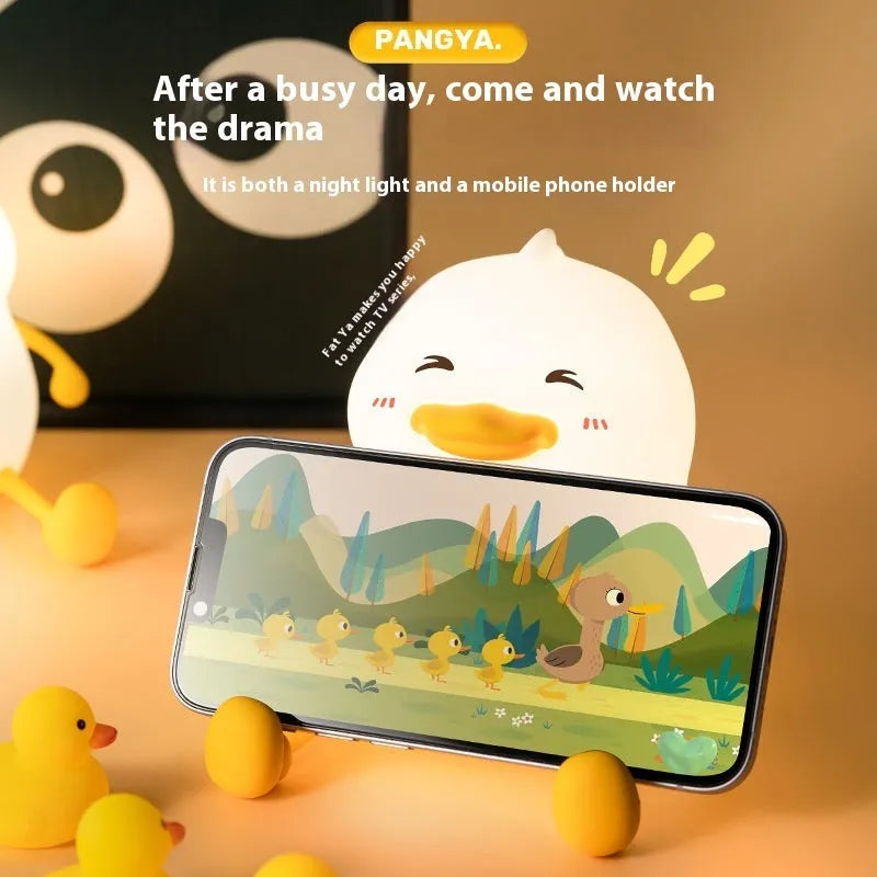 Chubby silicone desk night lamp with integrated mobile phone holder showing soft glowing light.