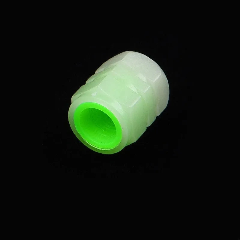 Black rubber luminous car tyre valve cap with glow-in-the-dark tip, shown next to a coin for scale.