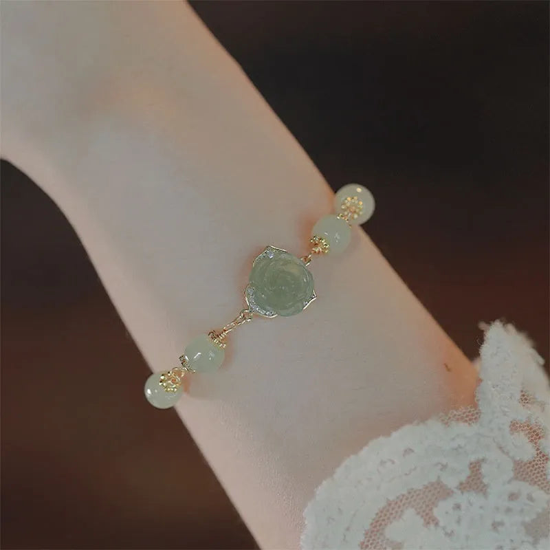 Close-up of a women's Hetian Jade bracelet with rose design and 14K gold gilding.