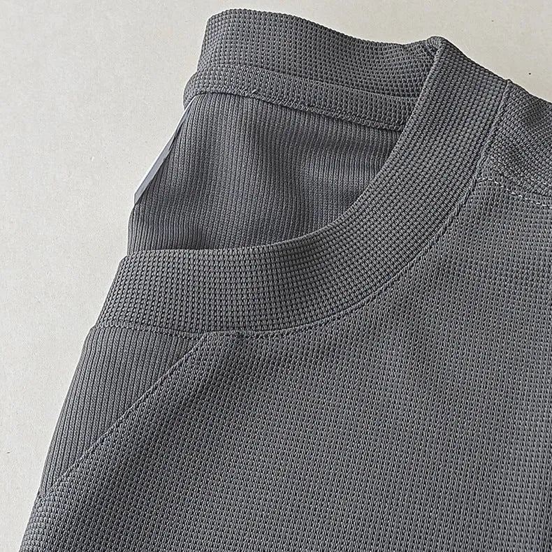 Men's dark grey waffle-knit short sleeve T-shirt showing textured fabric detail.