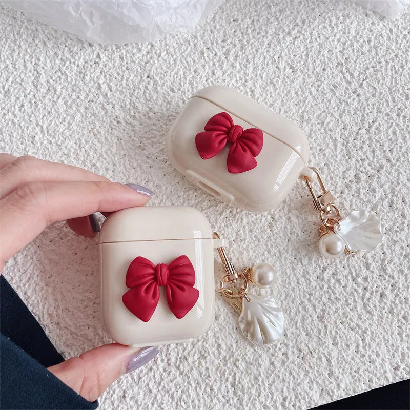 Beige AirPods case with red bow decoration, clamshell design for AirPods Pro and AirPods 3 models