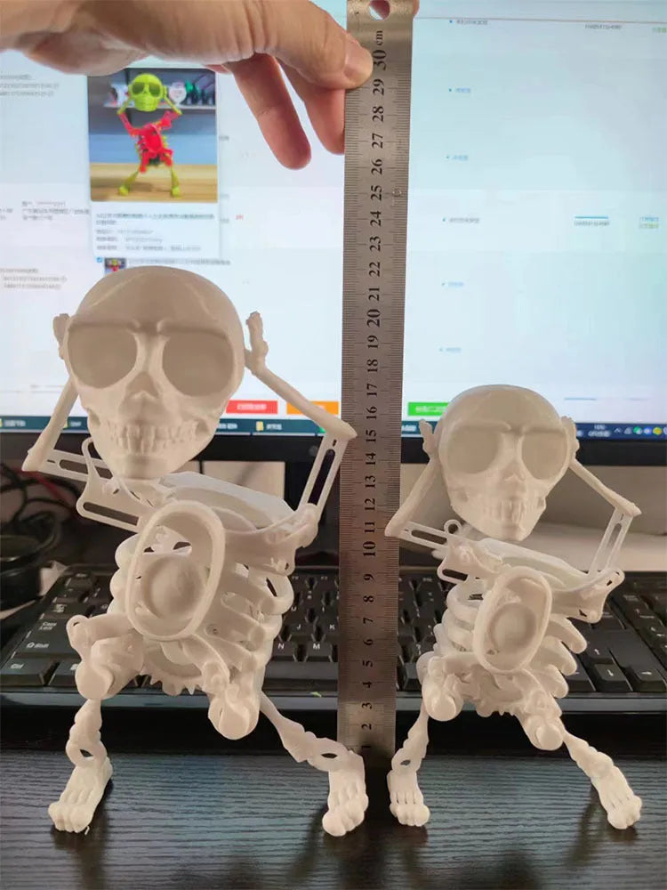 3D printed dancing skeleton gravity toy in pink and white, 22cm tall, on a desk