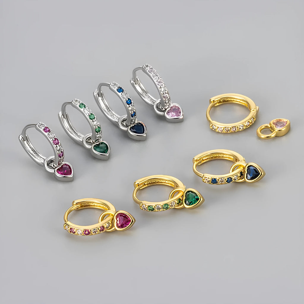 Close-up of women's fashion clip-on earrings with a heart-shaped pink cubic zirconia stone in a gold-coloured copper setting.