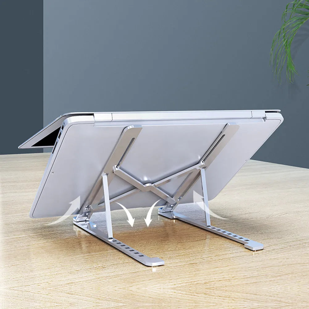 A folded aluminium laptop stand in rose gold next to an open silver laptop on a desk.