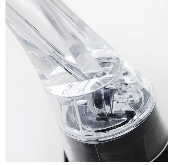 Clear acrylic wine aerator with stainless steel filter, shown next to a wine glass.