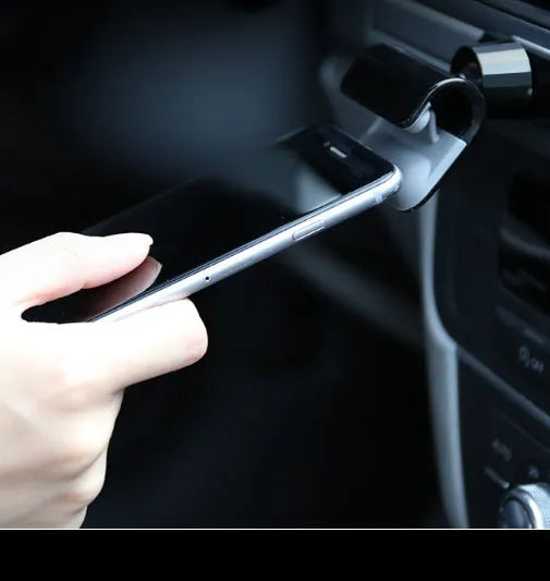 Black 360-degree rotating car phone holder mounted on a car air vent, showing a mobile phone secured in the cradle
