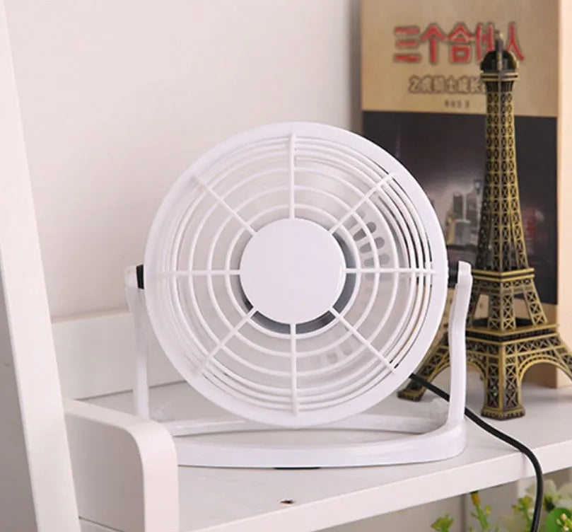 Mini USB desk fan with adjustable angle in black colour beside laptop