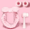 Purple, grey, white, and pink facial brush set with coral fleece hair band and nylon bristles.