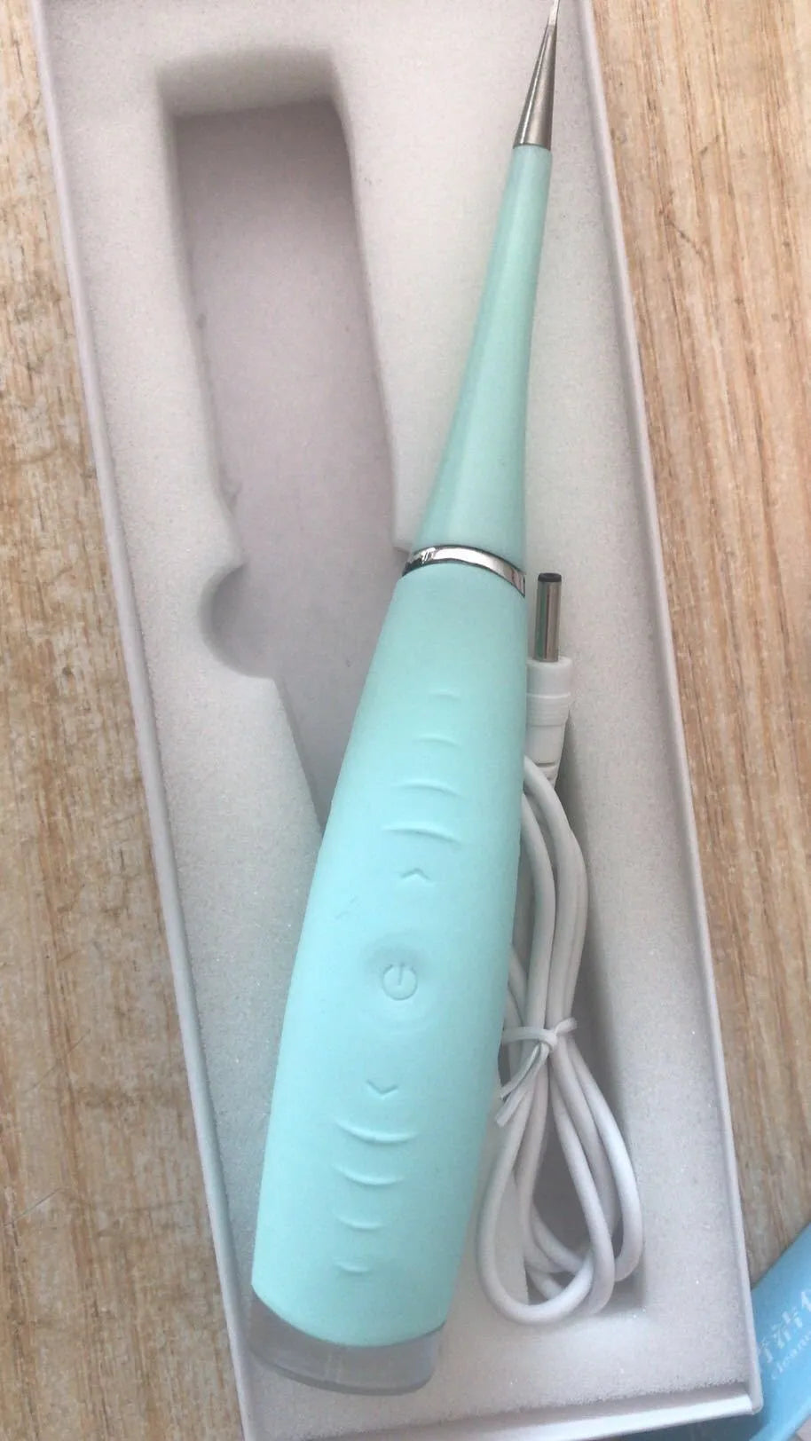 Pink and blue waterproof electric tooth scaler with integrated handle on a bathroom counter.