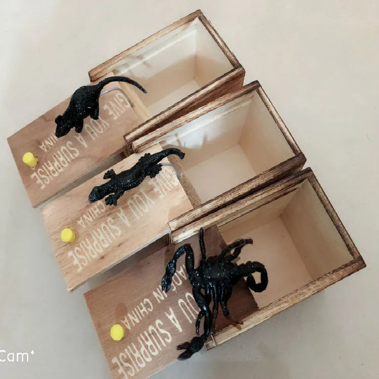 Wooden prank scare box with lid open showing a lifelike spider figurine on a spring.
