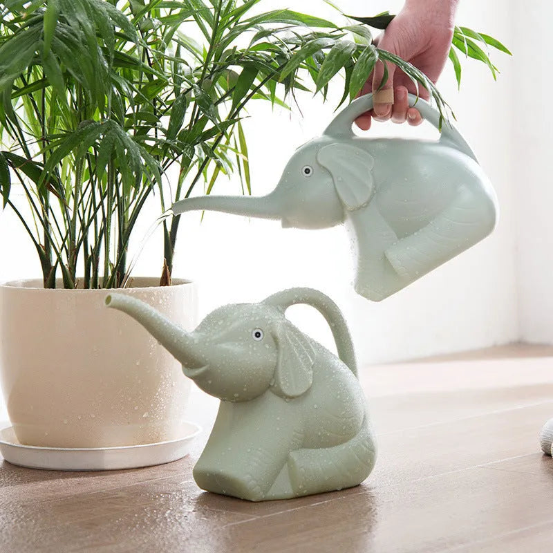 Pink baby elephant-shaped watering can with a long nozzle and bottle-style handle on a table.