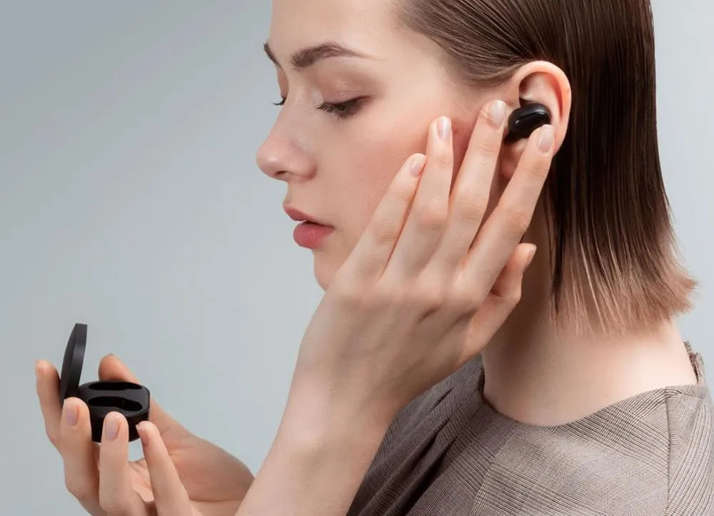Redmi AirDots black true wireless earbuds and charging case on a table.