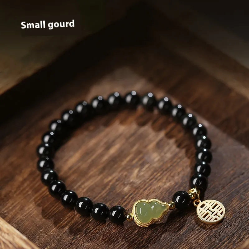 Black obsidian bracelet with a Hetian jade gourd pendant, showing geometric beads.