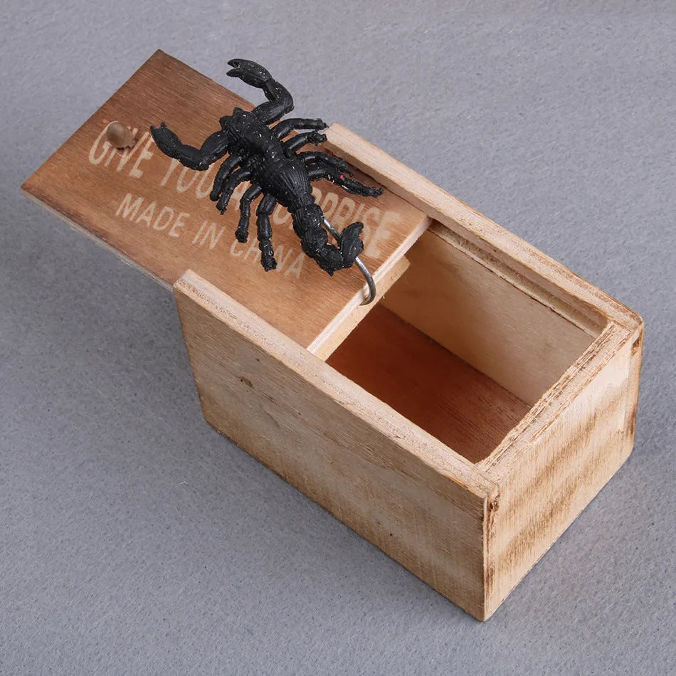 Wooden prank scare box with lid open showing a lifelike spider figurine on a spring.