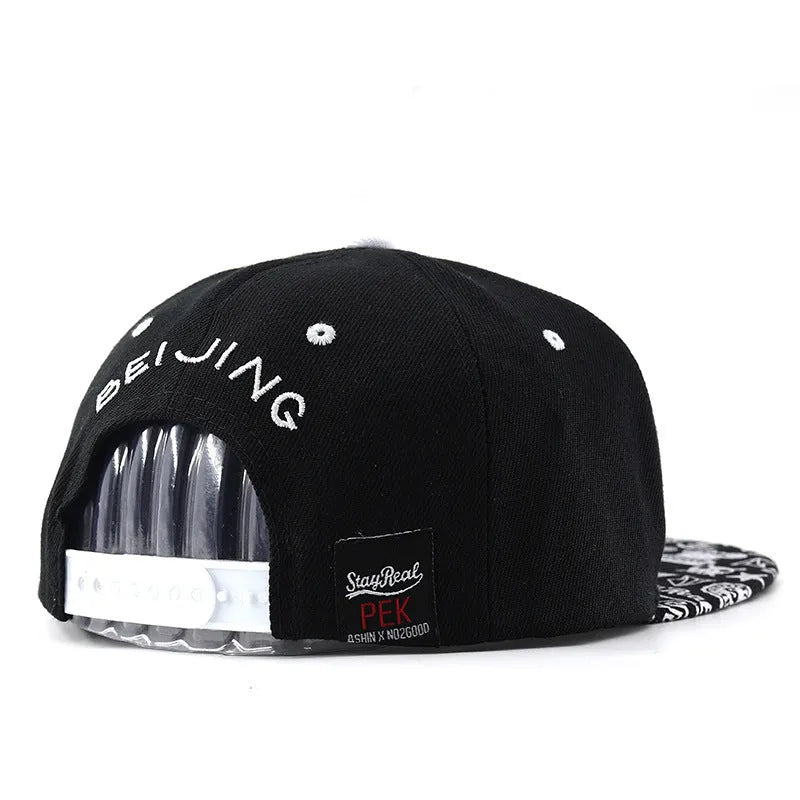 Black cotton baseball cap with white letter embroidery on the front, showing adjustable strap.