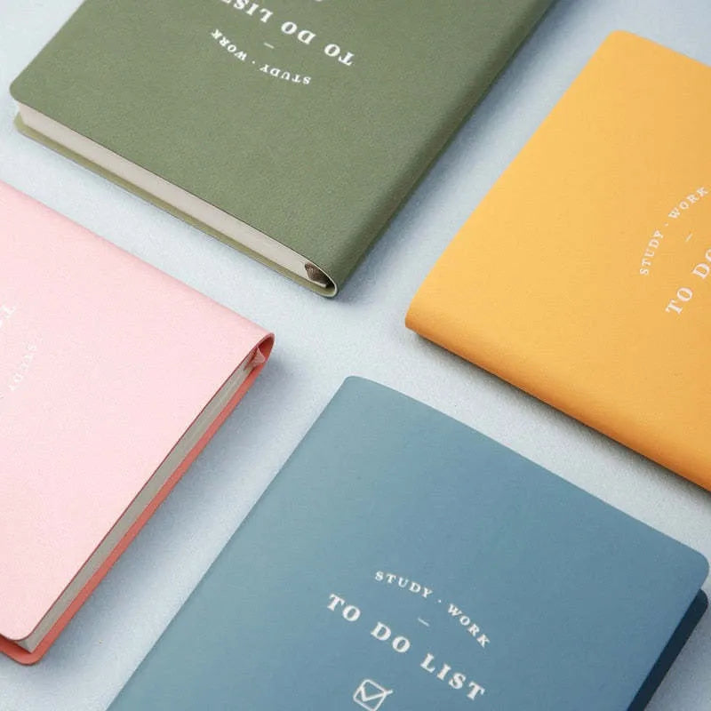 A simple portable todolist notebook in morandi blue with a PU cover, shown next to a pen.