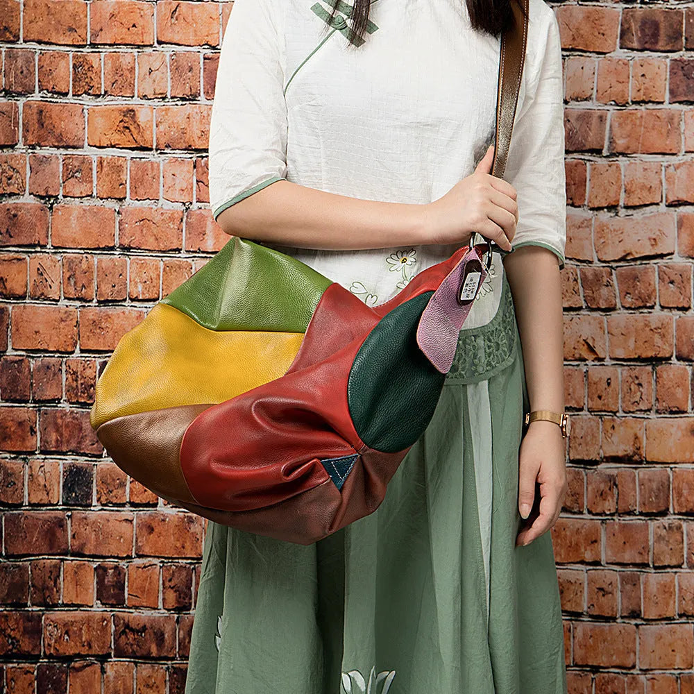 Brown cowhide leather travel bag with stitching, shown as a crossbody bag with a laptop and iPad inside.