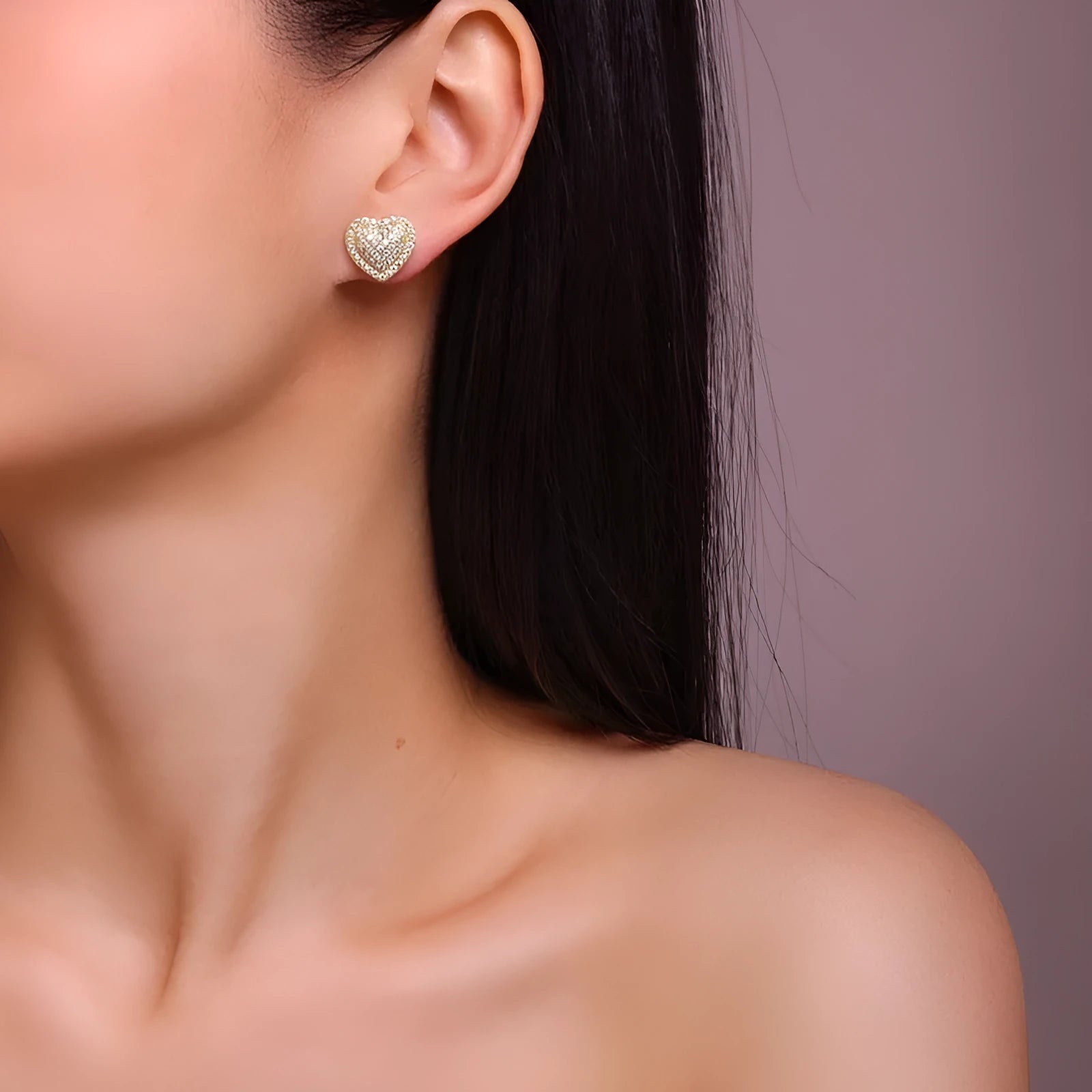 A pair of golden heart-shaped stud earrings with moissanite stones on a grey background.