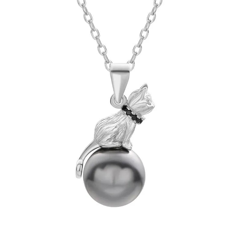 Close-up of a delicate sterling silver cat pendant on a thin clavicle-length chain.